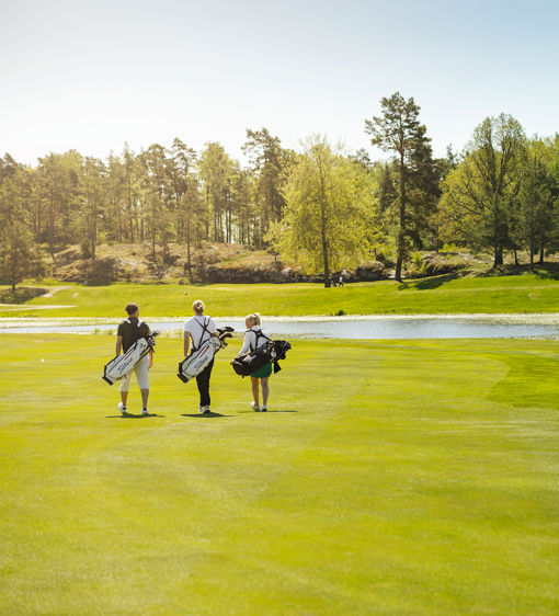 Tre människor går på golfbana