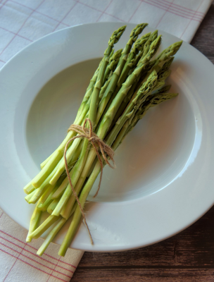 Grön sparris ligger på en djup tallrik