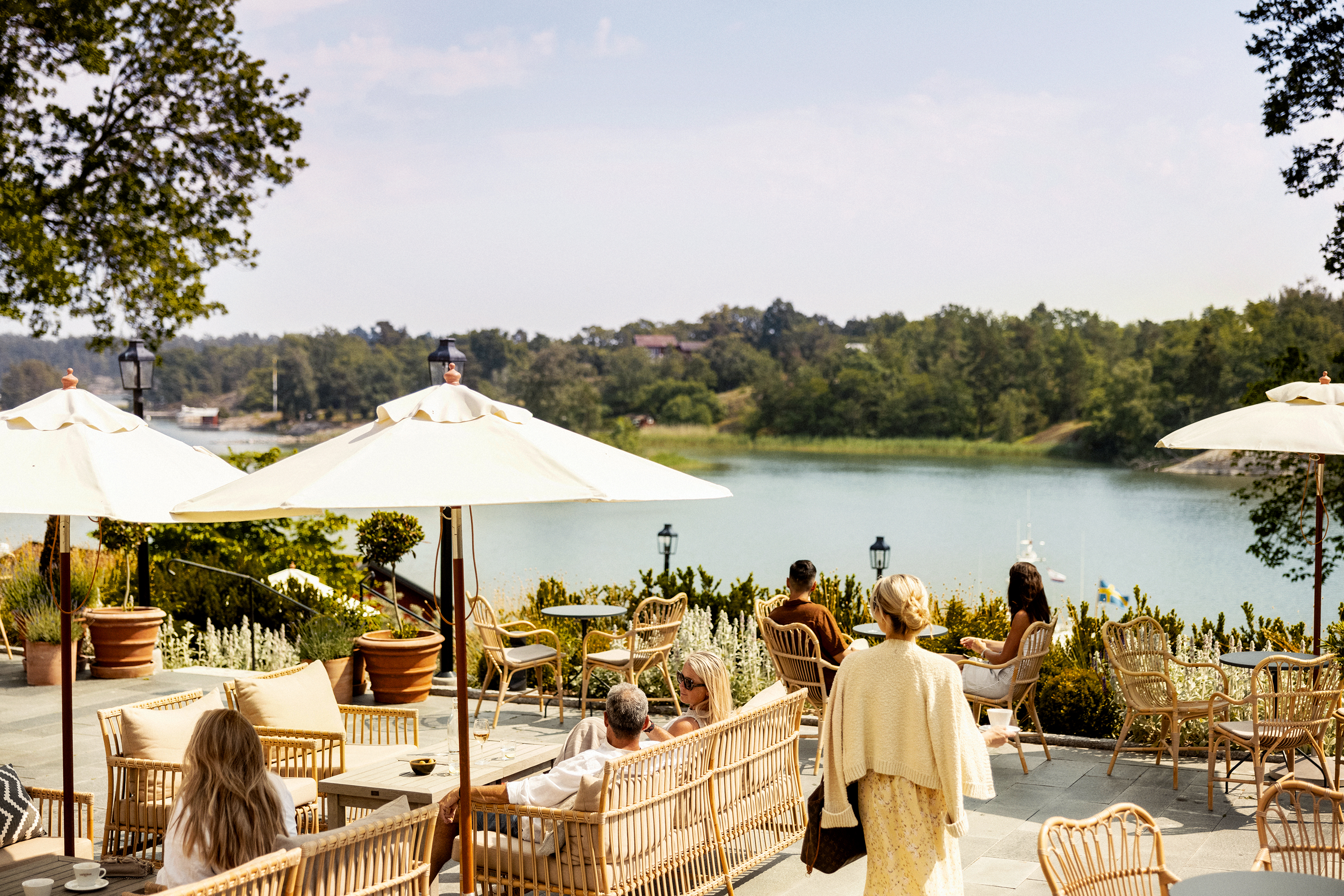 Personer njuter i solen på uteplatsen med utsikt över Hemviken
