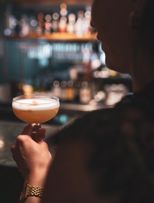 Person dricker en rosa drink i baren