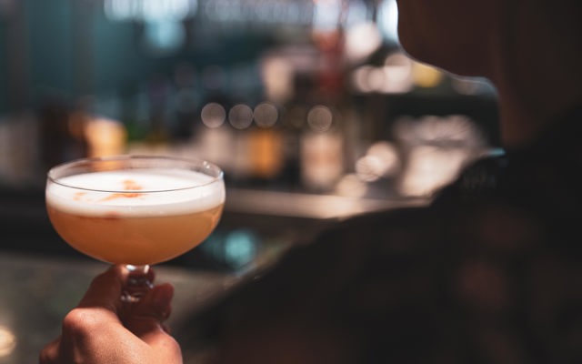 Person dricker en rosa drink i baren