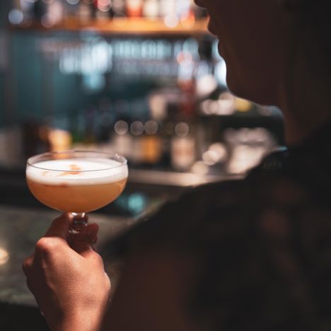 Person dricker en rosa drink i baren