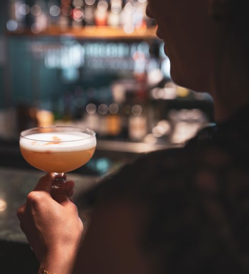 Person dricker en rosa drink i baren