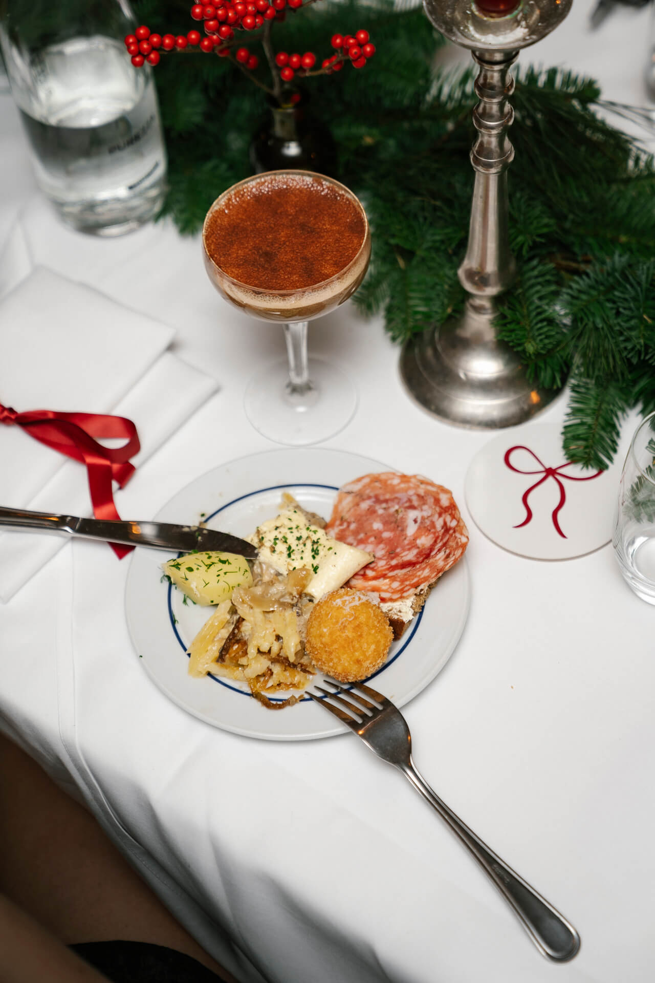 Tallrik med olika rätter från julbord och dessert i ett högt glas