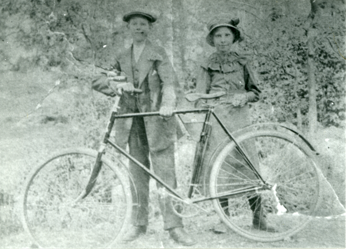 Historiskt foto på två barn och en gammeldags cykel