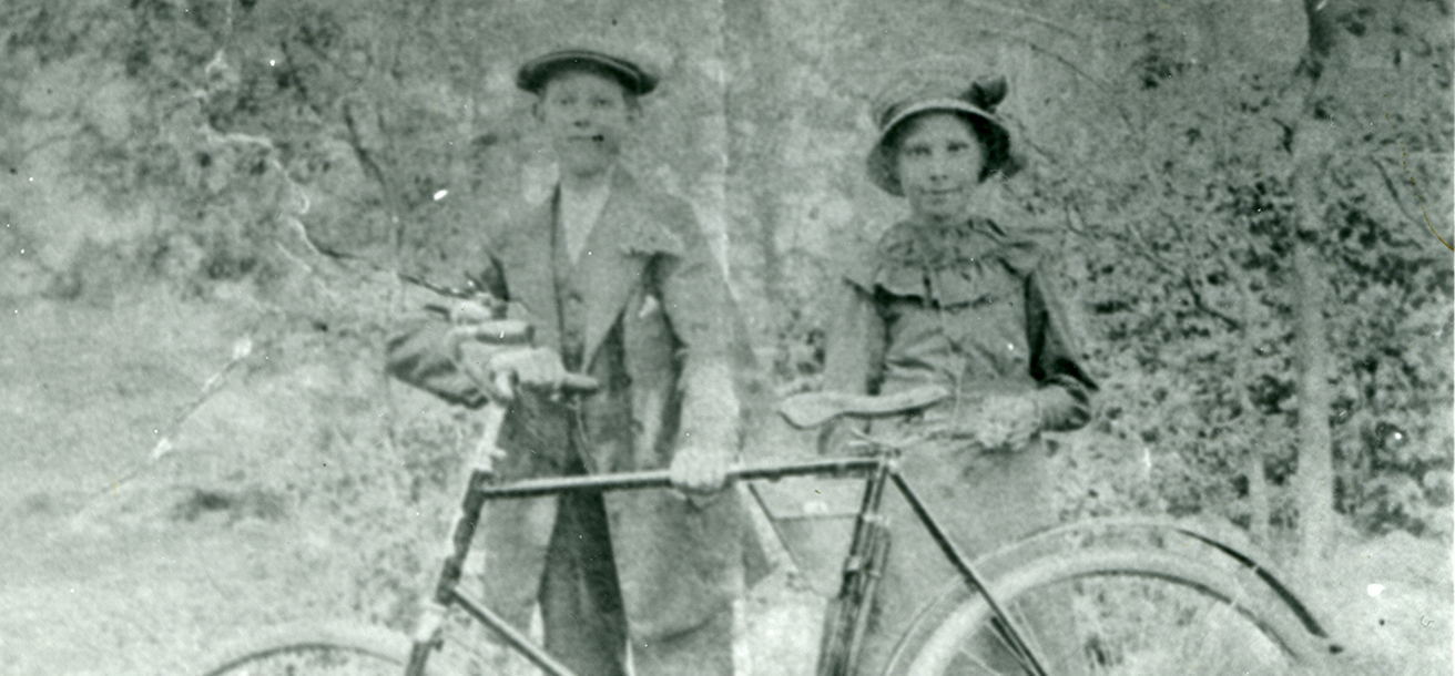 Historiskt foto på två barn och en gammeldags cykel
