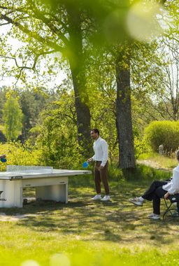 En grupp spelar pingis utomhus omgiven av vacker natur