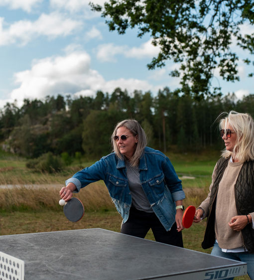 Två kvinnor spelar pingis utomhus vid hotellet