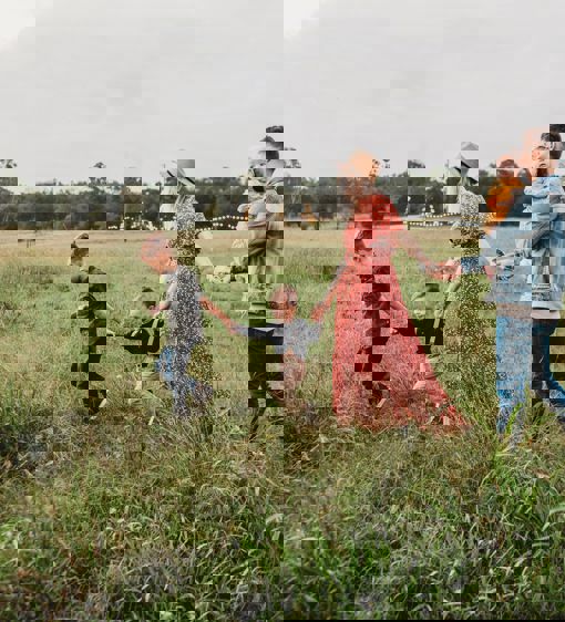 Familj går över en sommargrön äng på landet