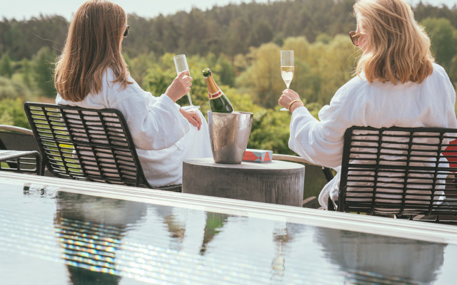 Två kvinnor dricker champagne vid utomhuspoolen