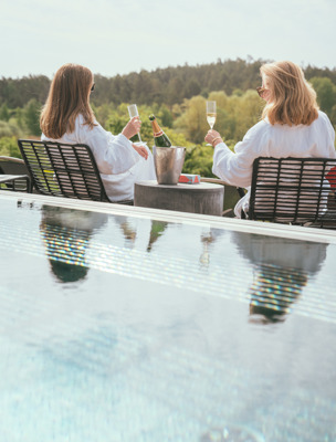 Två kvinnor dricker champagne vid utomhuspoolen