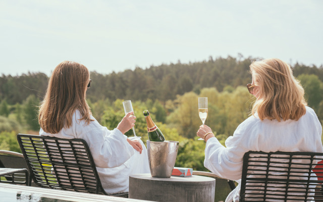 Två kvinnor dricker champagne vid utomhuspoolen