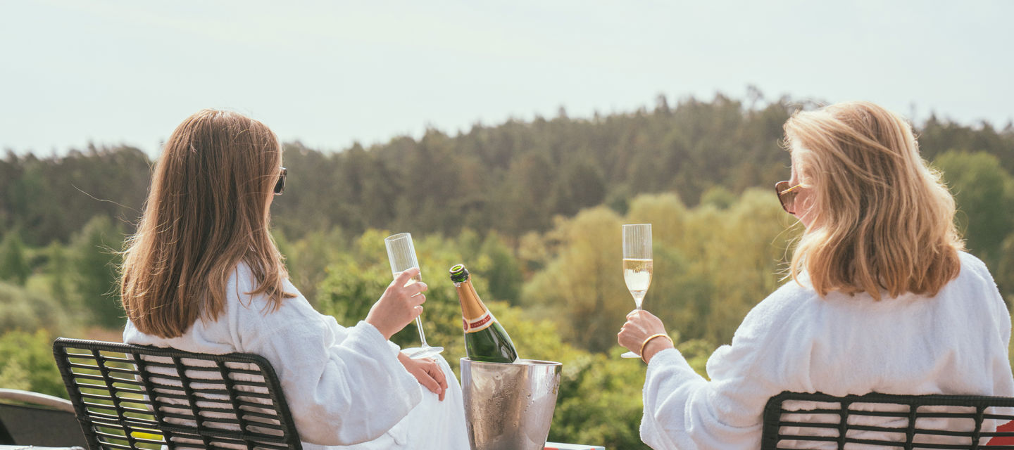 Två kvinnor dricker champagne vid utomhuspoolen
