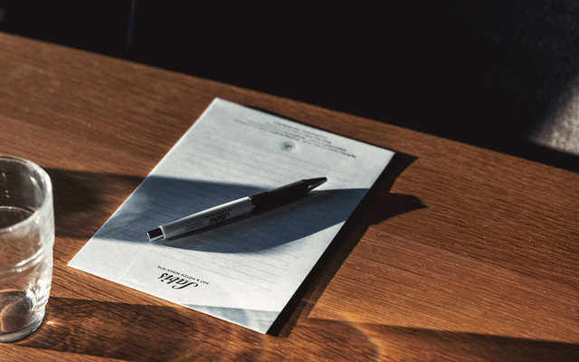 Ett anteckningsblock och penna ligger på ett träbord