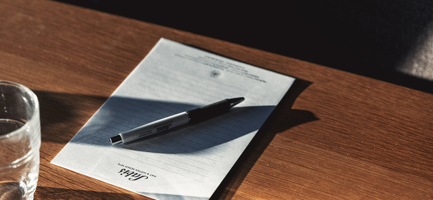 Ett anteckningsblock och penna ligger på ett träbord