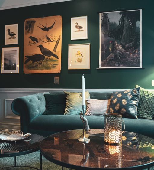 Salong med mörkgröna färger på soffor och väggar