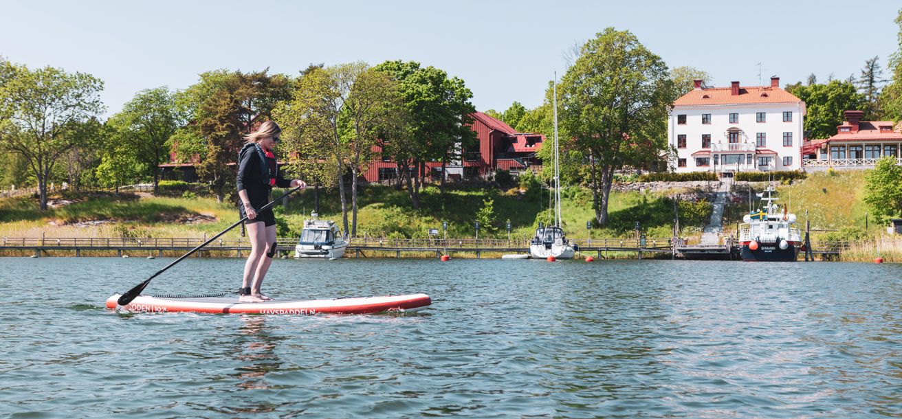 Kvinna åker SUP i vacker skärgårdsmiljö