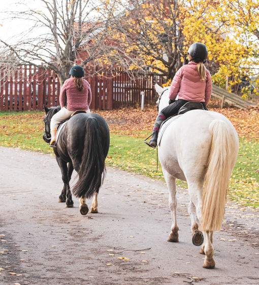 Två barn rider på varsin häst