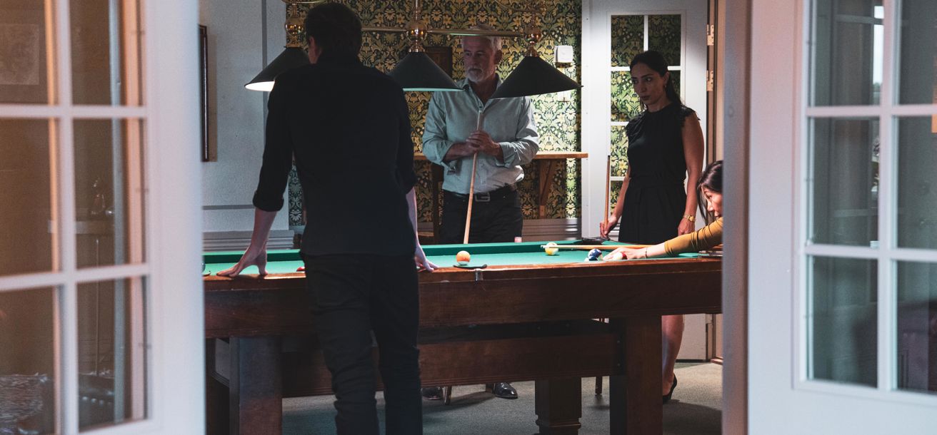Grupp spelar biljard i vacker salong