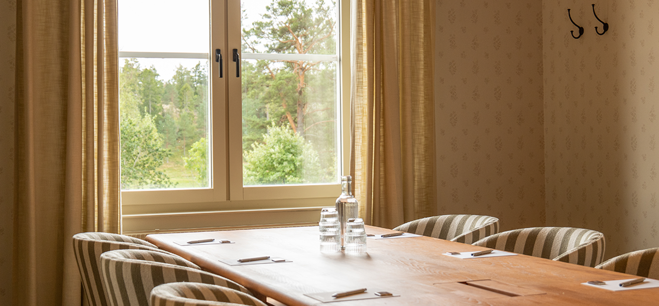 Konferensrum i ljusa färger, möblerad i styrelsesittning