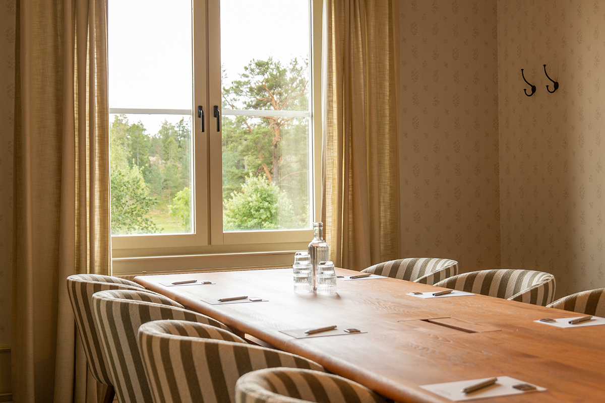 Konferensrum i ljusa färger, möblerad i styrelsesittning