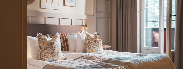 Bäddad hotellsäng i ett rum med tillhörande balkong