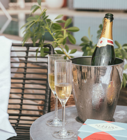 Champagneflaska i ishink, två glas och sällskapsspel vid utomhuspoolen